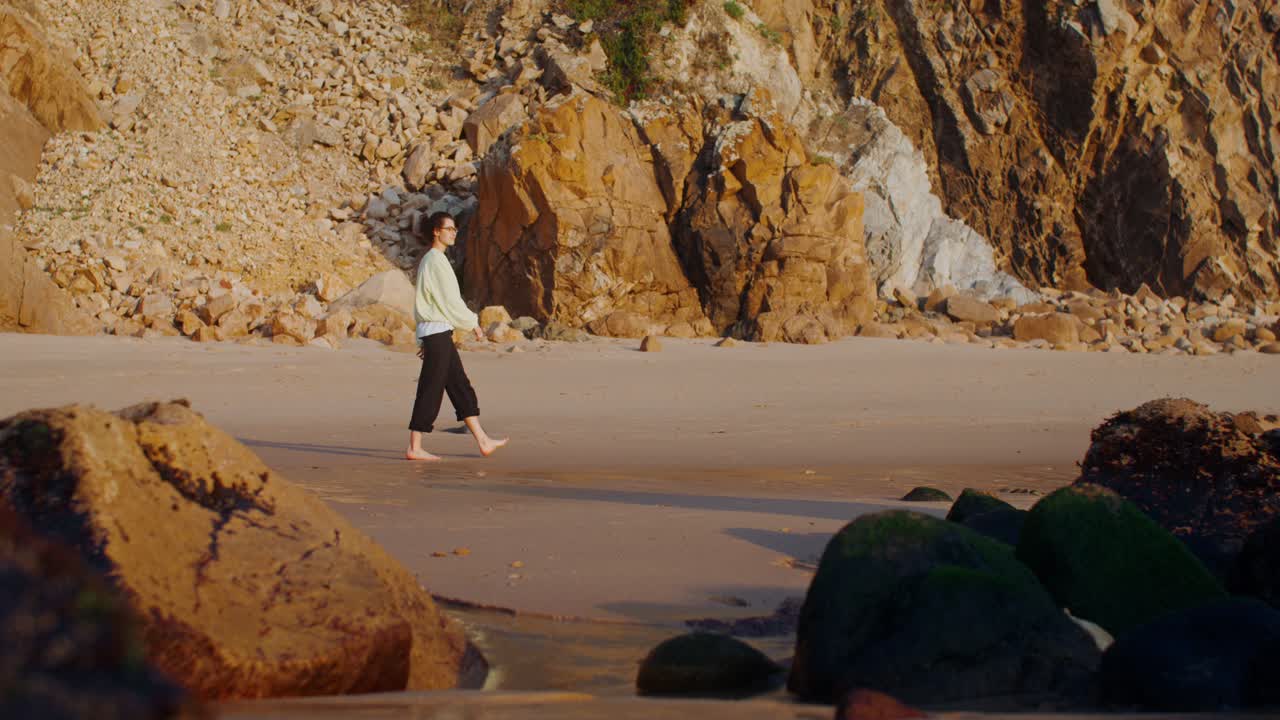 mujer caminando por una playa de arena al atardecer