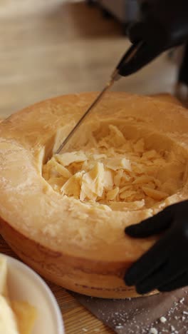 cutting a wheel of parmesan cheese