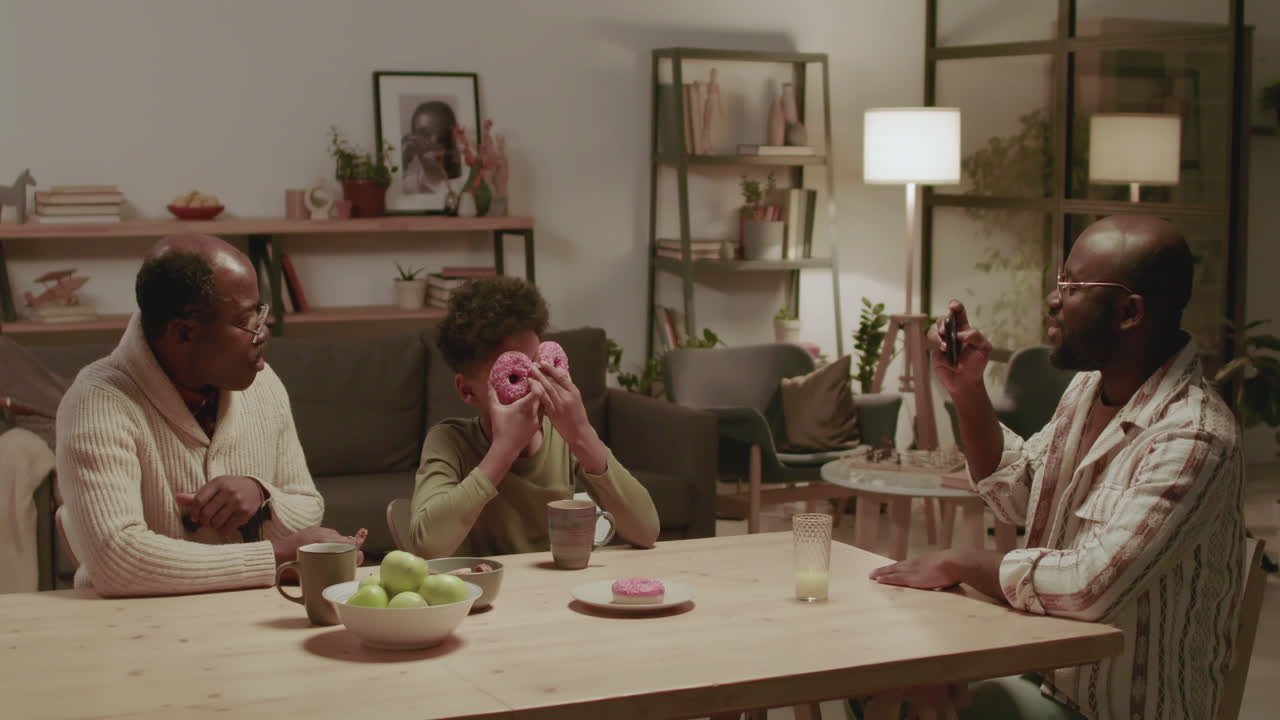 흑인 남성과 소년이 집에서 식사하면서 즐거운 시간을 보내고 있습니다.