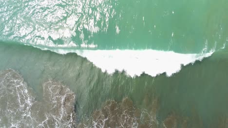 top down aerial drone view, lone wave crashes into white foam