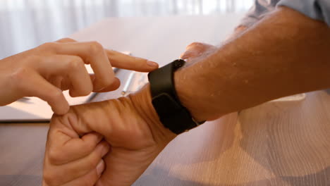 hombre mostrando un reloj inteligente a una mujer
