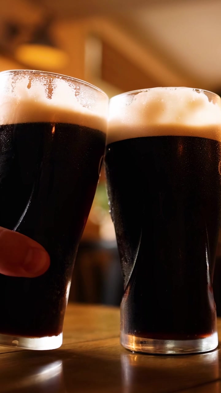 Due pinte di birra scura che tintinnano