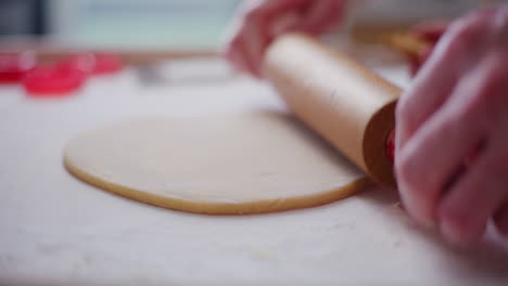 man rolls out pizza dough close up