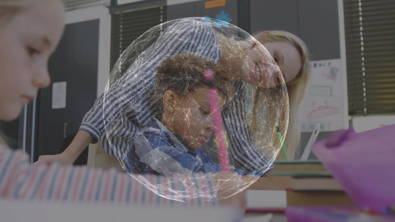 Teacher leaning in over boy writing in class helping with pink pen while globe overlay appearing