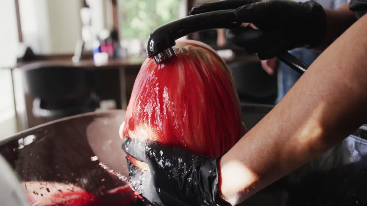 Vista posteriore di una donna che si fa lavare i capelli da una parrucchiera