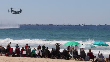 osprey aircraft performs over crowded beach and sea