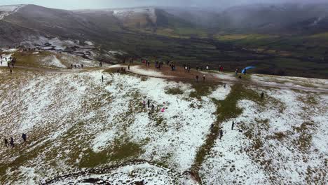 aerial view mam tor, peak district mountain reveal shot with paraglider taking off