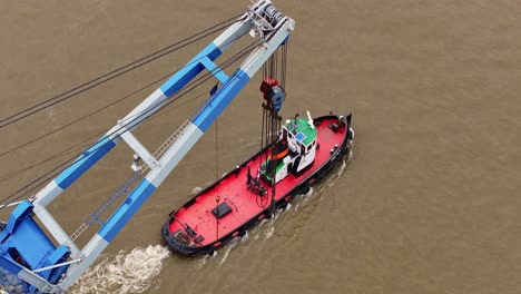 tug boat towing industrial crane platform on river with sense of purpose