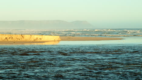 Heavy-flow-of-Klein-River-lagoon-as-it-breached-into-Walker-Bay,-sunset