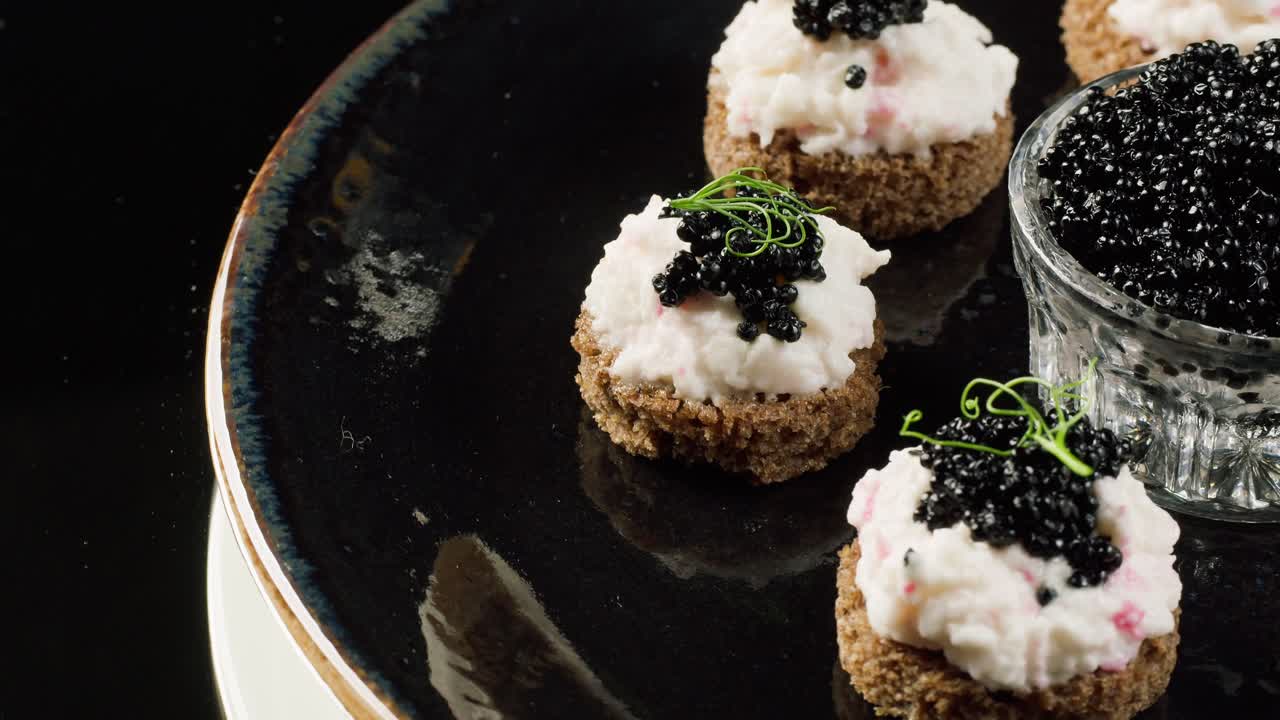Elegante canapéer med sort kaviar og cremet smørelse på mørkt brød
