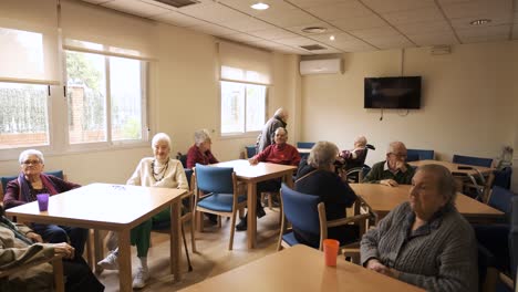elderly men and women sitting in nursing home canteen