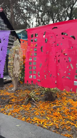 colorful papel picado with virgin of guadalupe statue during day of the dead celebration