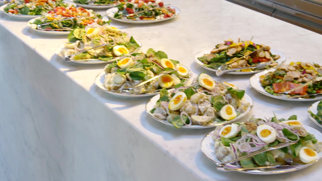 Un'ampia selezione di insalate gourmet, incluse insalata di patate cremosa con uova alla coque e vivaci insalate di cereali con verdure fresche e semi