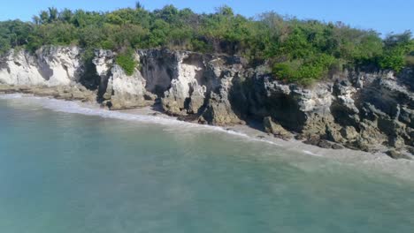 Lateral-flight-from-Macao-in-La-Altagracia-Dominican-Republic-province-view-of-the-cliff-and-blue-waters,-clear-day