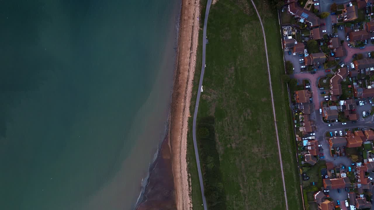 Birds-eye aerial view of Weston Shore Southampton, showing sandy beach, autumn trees, and calm blue sea under warm sunset light, creating a tranquil and scenic coastal atmosphere