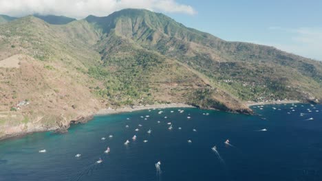 mountain slope on bali shore at pantai kusambi beach, cove with outrigger boats