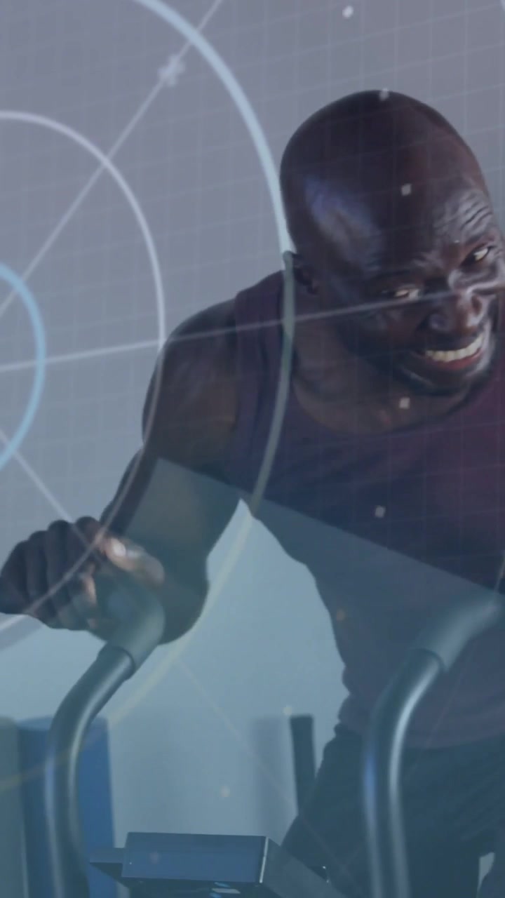 Vertical video: Man leaning, gripping bars, starting pedaling on bike while HUD tracking fitness