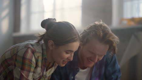 joyful family sitting on floor during apartment repair. couple laughing indoors.