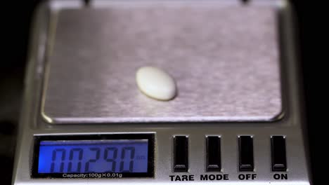 weighing a pill on a digital scale