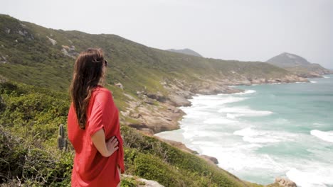 model caucasian cantik mengagumi pemandangan indah praia brava dari pegunungan tinggi di arraial do cabo, rio de janeiro, brasil