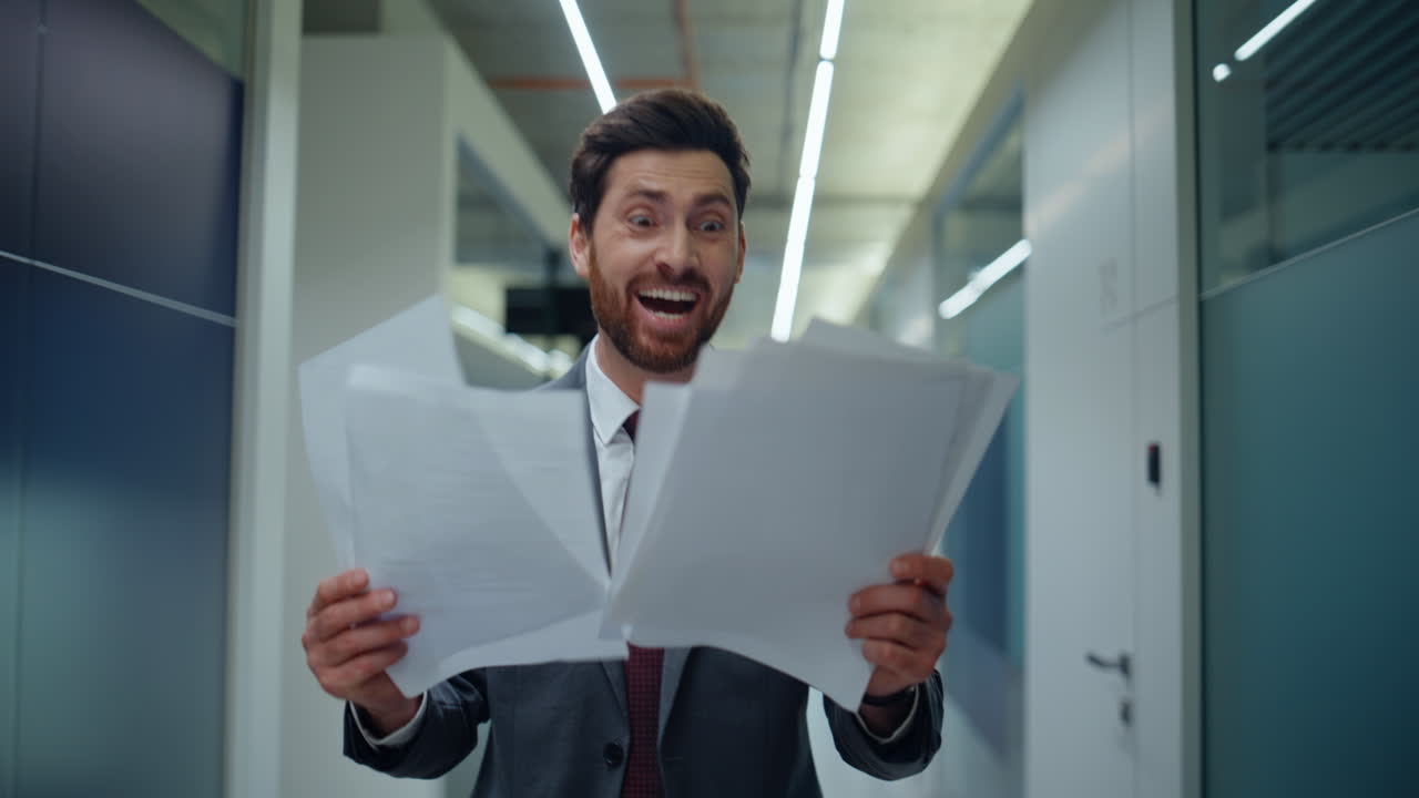 Närbild på specialist som granskar papper och känner sig exalterad och överlycklig i kontorskorridoren