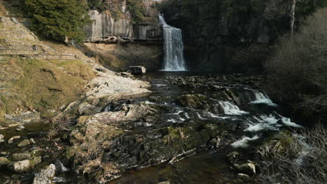 Approach-to-slow-motion-waterfall-with-running-stream-at-Ingleton-Waterfalls-Trail-Yorkshire-UK