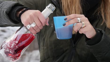 primer plano de verter vino mientras disfruta de un día de invierno nevado afuera