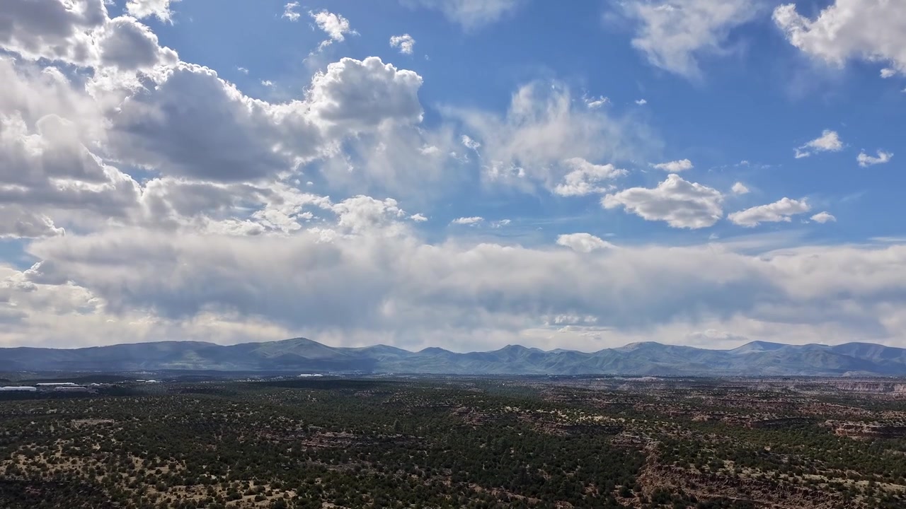 Timelapse con drone in ascesa che cattura nuvole dinamiche che si muovono su vaste mesas desertiche. Ombre mutevoli si estendono magnificamente sul paesaggio aspro del sud-ovest mentre le condizioni meteorologiche si formano