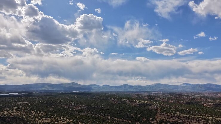 Timelapse aéreo ascendente que captura nubes dinámicas deslizándose sobre vastas mesetas desérticas. Sombras cambiantes se extienden bellamente por el escarpado paisaje del suroeste mientras se desarrollan fenómenos atmosféricos.