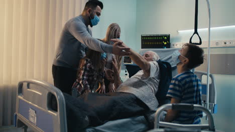 family visiting elderly grandfather in hospital