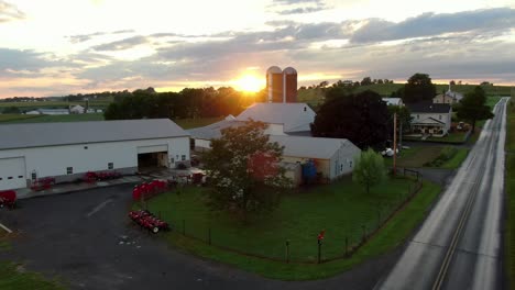 establishing shot of small american family farm, barn, buildings, silos at sunrise sunset with dramatic flare effect