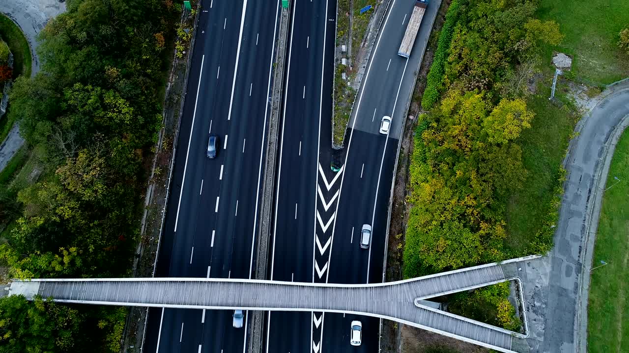 프랑스의 고속도로 교차로 위에서 공중에서 볼 수 있는 모습: 도로 주변의 집과 풀, 도로를 달리는 자동차와 트럭.