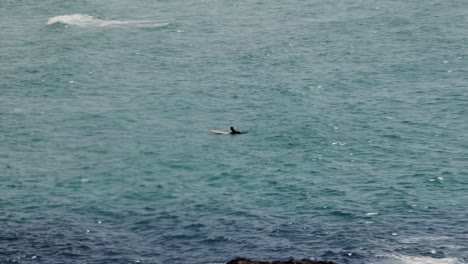 Hand-held-shot-of-a-surfer-lying-on-his-board-waiting-on-a-wave-at-Fistral-Beach