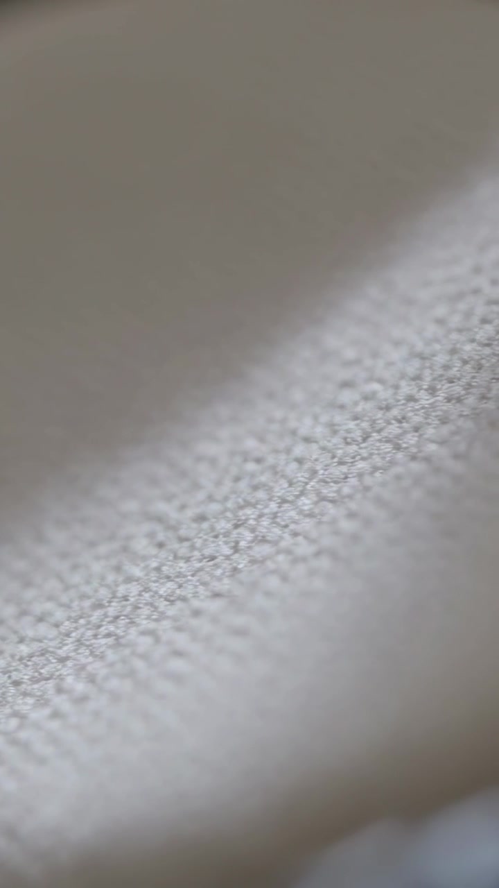 Vertical video: Scanning camera moving down-right over beige upholstery in car, showing dark trim