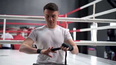 un atleta fuerte envuelve sus manos con vendas de boxeo antes de entrenar