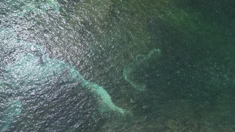 Aerial-birdseye-view-pan-across-oceanside-road-and-mopeds-towards-reef-and-ocean