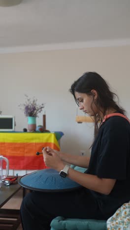 young woman playing a singing bowl at home