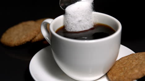 teaspoon pouring sugar into cup of coffee