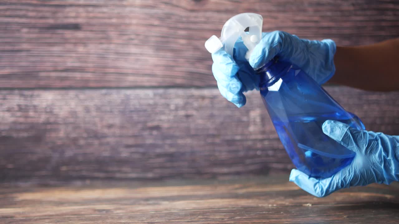 스프레이 병과 장갑으로 청소하는 사람