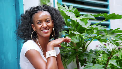 Fashionable-young-black-woman-sitting-in-a-doorway-laughing-and-talking,-close-up