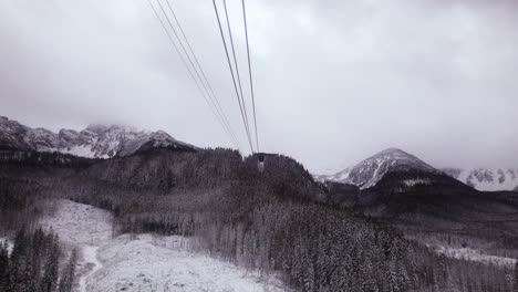 Blick-Auf-Die-Seilbahn,-Die-Den-Schneebedeckten-Berg-Kasprowy-Wierch-Hinunterfährt,-Mit-Linien-Hinüber-Zum-Tatra-Gebirge