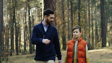 caucasian happy father and his little son walking and talking in the forest