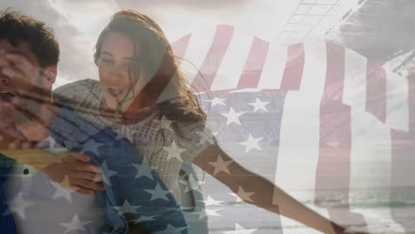 animation of waving flag of usa over couple having fun on the beach