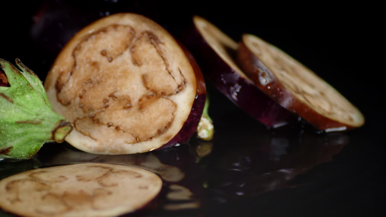 las rebanadas redondas de berenjena caen sobre las salpicaduras de agua.