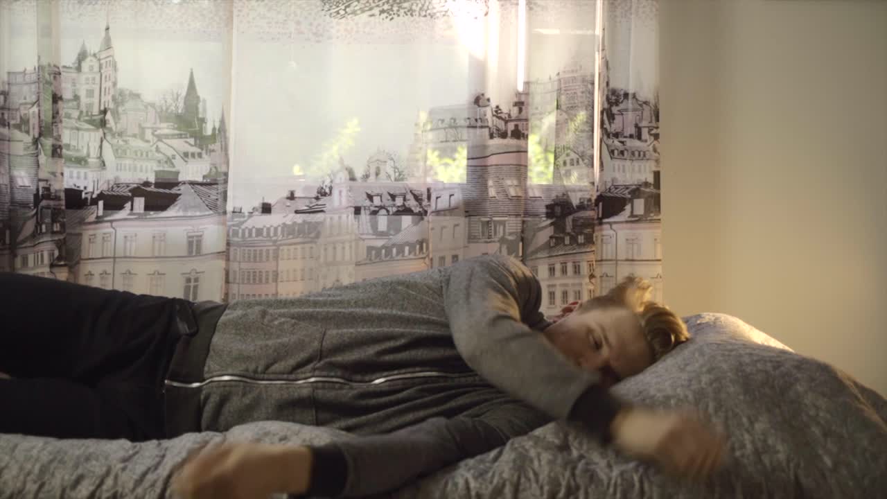 젊은 백인 남자가 휴식을 취하기 위해 침대에 누워