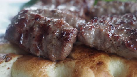 primer plano de cevapcici a la parrilla en una cama de pan plano