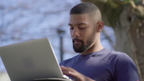 Afro-American-man-looking-around,-thinking,-typing-on-laptop