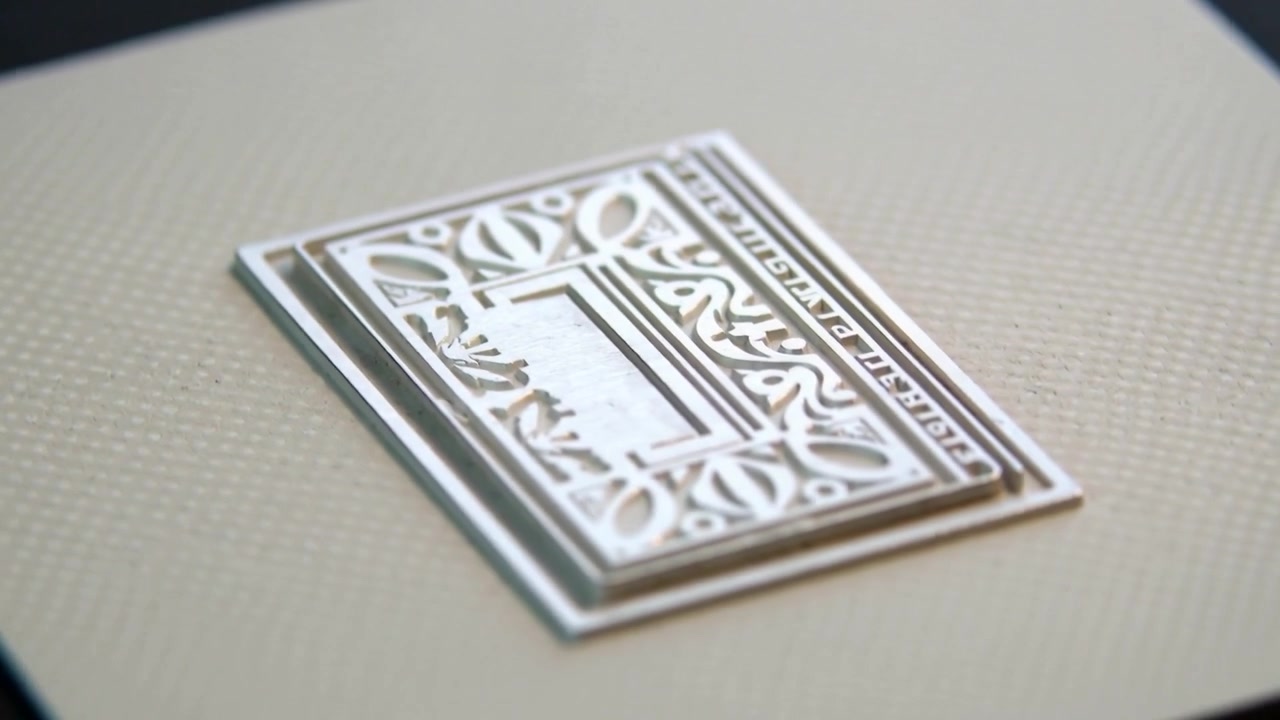Tilting camera panning clockwise revealing silver plaque on cream cardstock, showing highlights