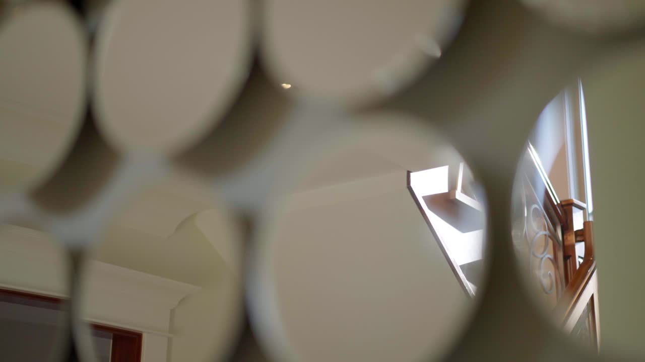 Una ripresa cinematografica del riflesso di un'elegante scalinata in una casa di lusso con la luce che risplende attraverso il riflesso