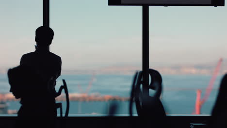 silhouette of businessman using smartphone having phone call chatting on mobile phone looking out window corporate executive discussing sales working late in busy office